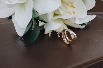Wedding rings and bouquet on brown background
