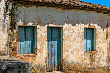 An old, abandoned house, ravaged by time, with its blue windows and crumbling plaster on the walls