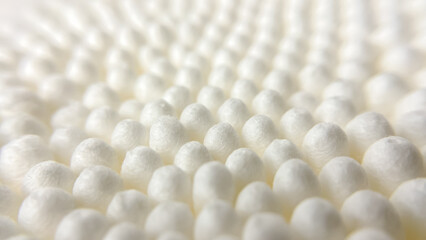 Rows of white cotton swabs create a soft, wavy pattern. A concept of cleanliness, order, and minimalist aesthetics.