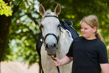 Obraz premium Girl with her beautiful white horse in nature, equestrian lifestyle, friendship and love, horse riding, outdoor activity, summer day, animal care, happy childhood.