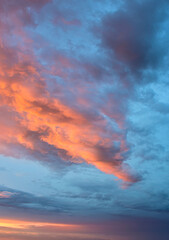 Brilliant sky illuminated by sunset colors spreading behind floating clouds