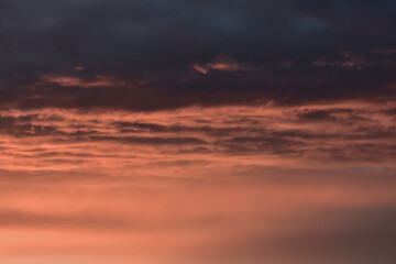 Colorful sunset sky shining warmly through delicate layers of clouds