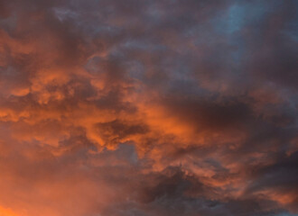 Luminous sunset sky casting vibrant hues across gentle and heavy clouds