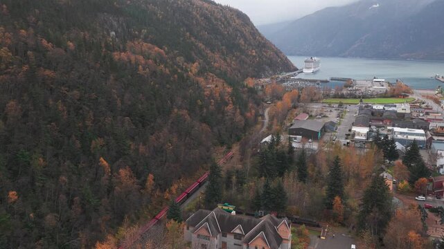 Aerial wide descending shot of the White Pass Yukon Route Railway arriving in Skagway during the fall season in Southeast Alaska. 4K