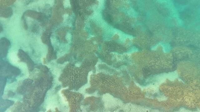 A stunning drone video over Tutupakul Lake in Kyrgyzstan, starting with clear turquoise water, then rising to reveal traditional yurts at the base of a majestic mountain range.
