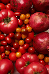 Pomegranate and assortment of red and yellow cherry tomatoes on a light marble surface