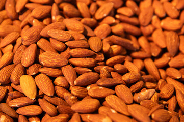 Almonds as a background. Whole brown shelled almonds, piled. Almonds, top view. Flat lay, packaging design element