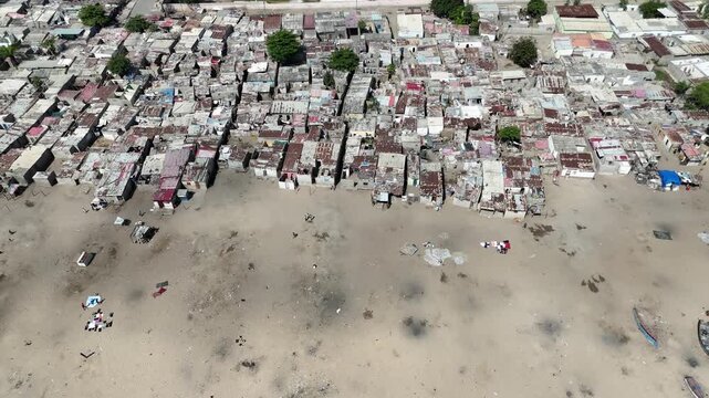 Drone top-down footage of Benguela, Angola, showing dense coastal housing and beachfront area under clear sky near the Atlantic Ocean