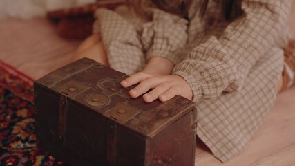 closeup of a child opening and closing an old wooden treasure chest with maps inside
