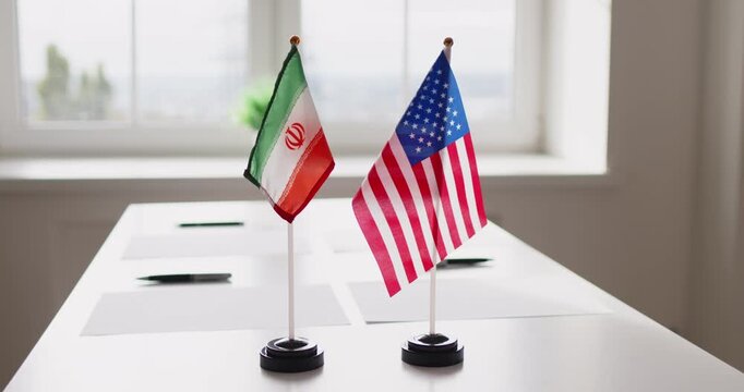 Flags diplomacy negotiations meeting partnership dialogue. Desk flags of Iran and USA on a conference table suggest geopolitics and agreement talks. Concept: international partnership and talks.