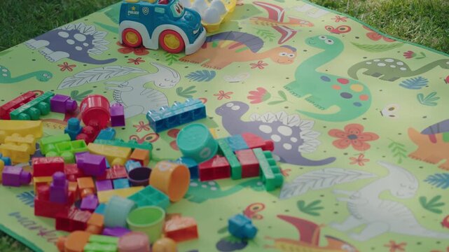 bright plastic toys scattered on a dinosaur play mat outside
