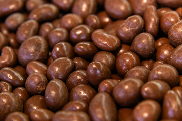 Close-up of brown dragee, chocolate covered nuts, sweet candy background.