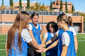 Young women football players making a huddle and putting their hands together, symbolizing unity and team spirit