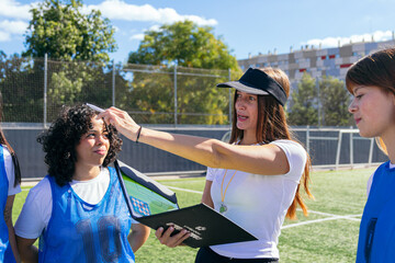 Female coach talking with women soccer players, explaining game strategy and tactics on the field during training session