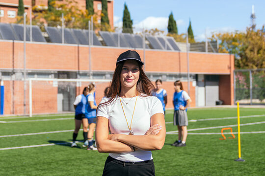 Confident woman coach supervising a group of young female soccer players during outdoor training session on a sunny day - Powered by Adobe