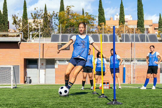 Female athletes practicing soccer drills on a field, improving control and technique during a sunny outdoor training session - Powered by Adobe