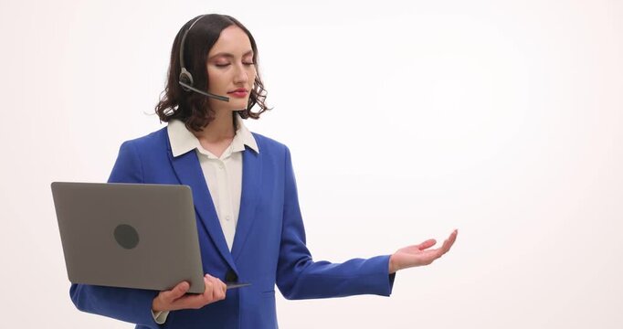 Woman with headset presents product gesturing near screen. Female holds laptop explaining features while preparing for client questions slow motion