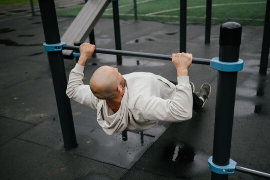 Man Performing Inverted Row on Outdoor Gym Equipment