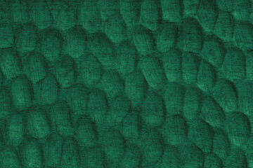 Textured green wooden surface with carved oval patterns and visible wood grain. Abstract texture...