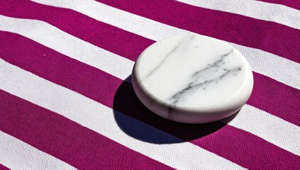 White marble disk rests on a vibrant striped fabric.