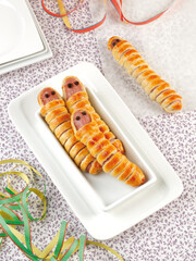 Sausages wrapped in puff pastry shaped like a Halloween worm.