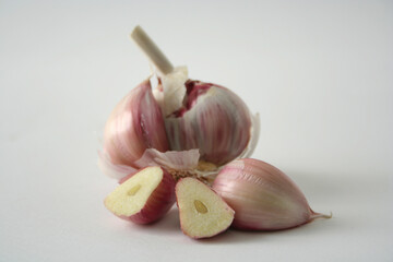 Head of garlic with a clove cut in half on a white background.