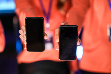 A diverse man and woman present smartphones with blank screens, perfect for a new app mockup. A showcase for mobile communication technology in a modern office setting.