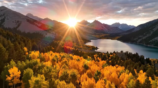 The sun rises over the majestic mountains, casting golden rays on the vibrant autumn trees surrounding the calm lake. The stunning landscape reflects nature's beauty in every direc