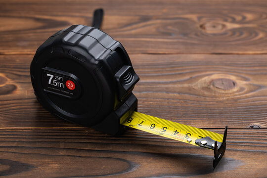Black tape measure on wooden background