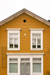 Yellow wooden house facade with white windows