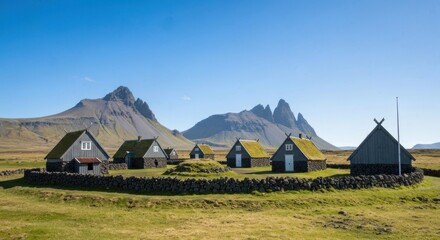 Small village with unique architecture & mountains in backdrop on a sunny day
