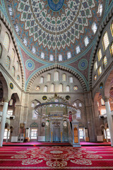 Burunguz Mosque interior, Kayseri, Turkey. Stunning Islamic architecture with an ornate dome, vibrant stained glass, and a richly patterned red carpet
