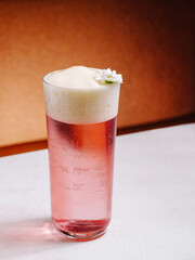 Refreshing pink drink with foam and flower decoration on a table