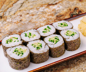 Fresh cucumber sushi rolls served on a wooden plate in a restaurant