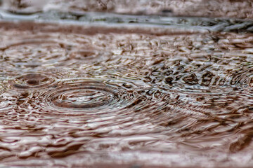 Rain falling on a clay tile floor forming puddles on it, close-up view captured in a farmhouse in the eastern Andean mountains of central Colombia, near the Iguaque natural reserve.