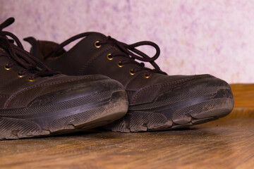 Close-up of Dusty, Dark Brown Leather Shoes or Boots on a Wooden Floor
