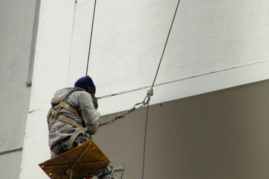 Industrial Abseiler Working on the High-Rise Facade with a Swinging Seat