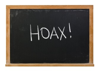 Hoax written in white chalk on a black chalkboard isolated in a wooden frame