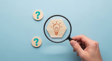 Magnifying glass focusing on idea bulb between question marks on blue surface