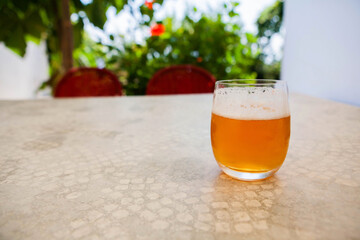 A glass of cool light beer on a summer table, glowing in warm sunlight. Refreshing seasonal drink scene perfect for leisure, relaxation, and outdoor summer vibes.