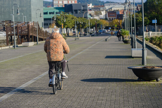 Old man is riding a bicycle down a sidewalk - Powered by Adobe