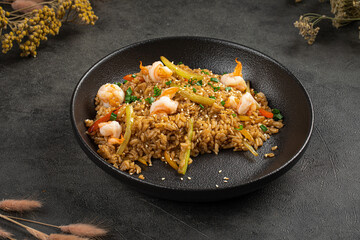 Savory fried rice cooked with shrimp vegetables sesame seeds and herbs served on dark plate