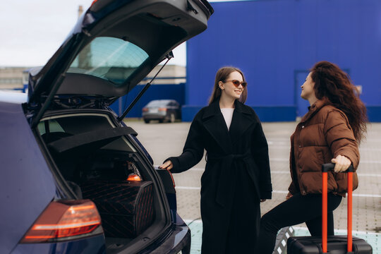 Women friends loading luggage into car - Powered by Adobe