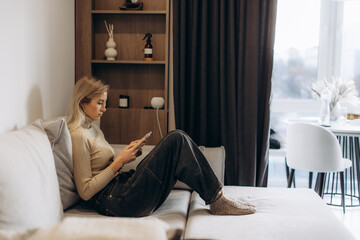 Woman relaxing at home checking smartphone