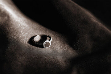 Pierścionek zaręczynowy położony na eleganckim materiale w miękkim świetle