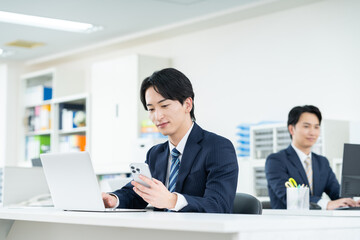 オフィスでスマホを使うビジネスマン