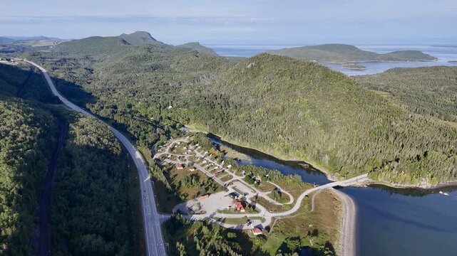 Aerial view of Bic National Park coastline, forest, campground and calm bay under blue sky. g.