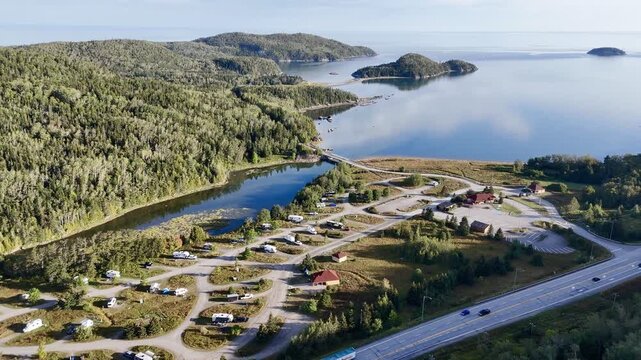 Aerial view of Bic National Park coastline, forest, campground and calm bay under blue sky. g.