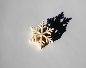 Single White Snowflake Ornament Casting a Sharp Shadow on a White Surface winter decoration