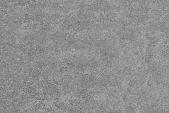 A uniform gray background featuring a subtly rough, mottled texture with slight variations in shade, creating an abstract, industrial surface